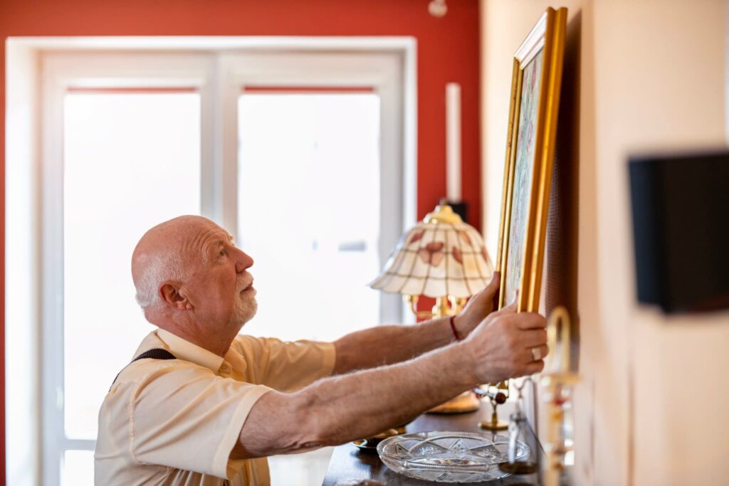 A person hanging a painting on a wall