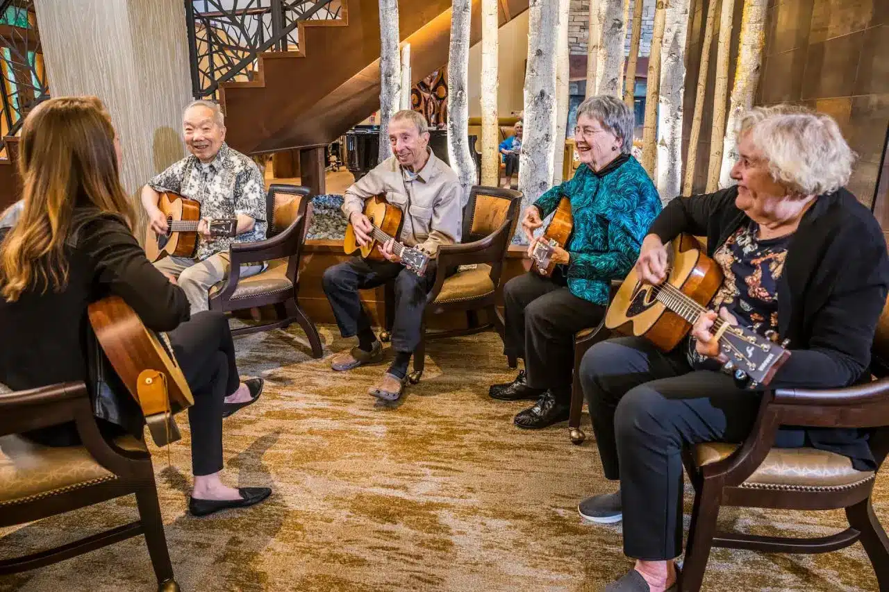 Seniors learn how to play acoustic guitar inside of an Aegis Living facility
