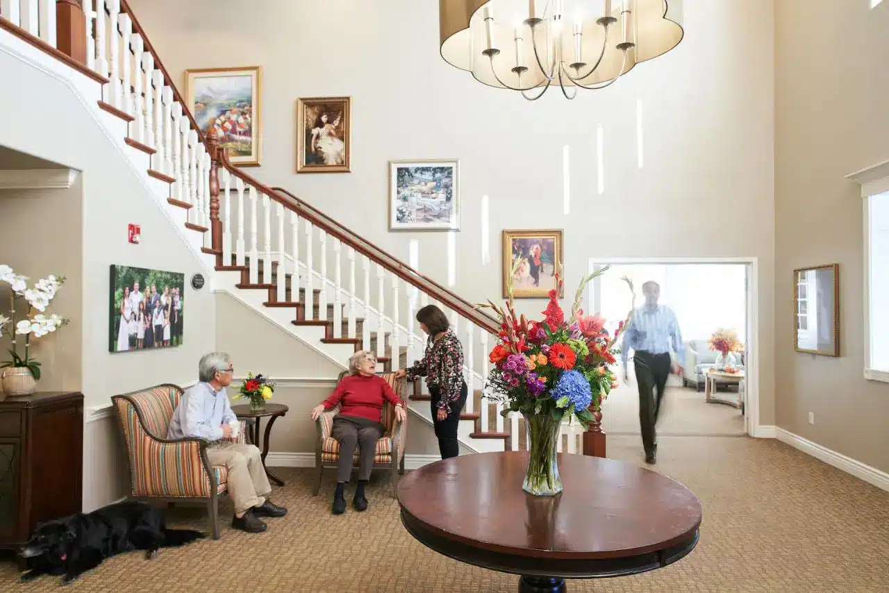Seniors and dog talking in front of a staircase