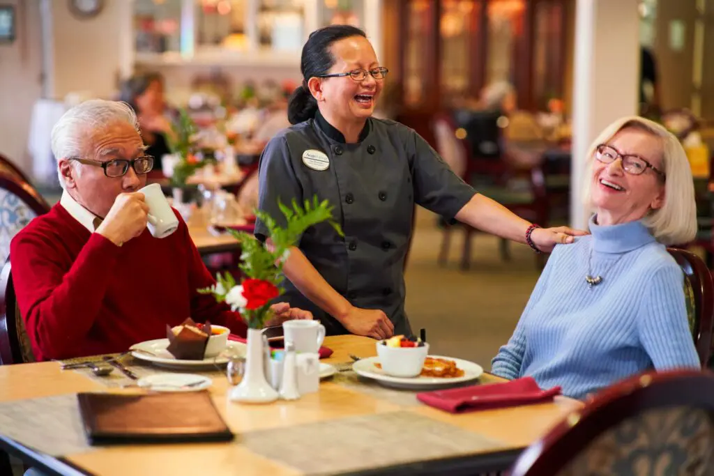 Happy seniors dining with staff in a restaurant.