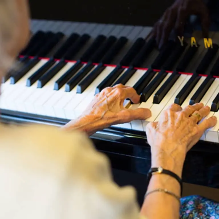 Elderly hands playing piano keys.